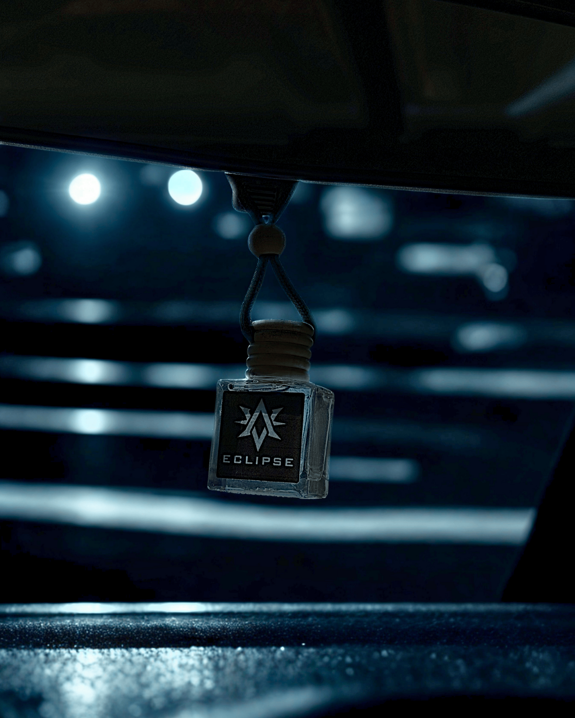 Eclipse car air freshener hanging from a hook in a car's interior.